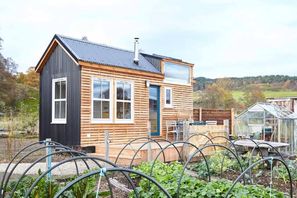 a small wooden house with a garden in front of it at Aileen - Unique tiny house with wood fired roll top bath in heart of the Cairngorms in Ballater
