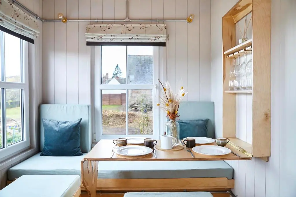 a dining room with a table and two chairs at Aileen - Unique tiny house with wood fired roll top bath in heart of the Cairngorms in Ballater