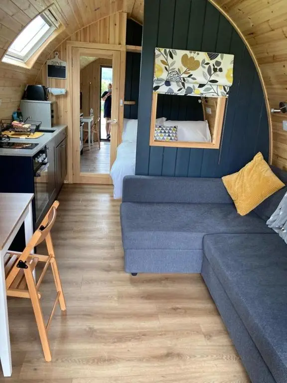 a living room with a blue couch in a tiny house at Owls Retreat Glamping Pod with Hot tub in Keith