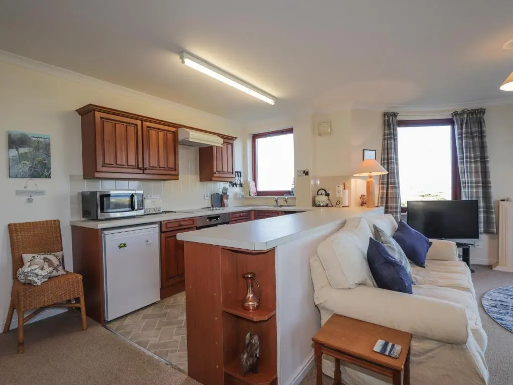 a kitchen and a living room with a couch and a table at Aurora View in Forres