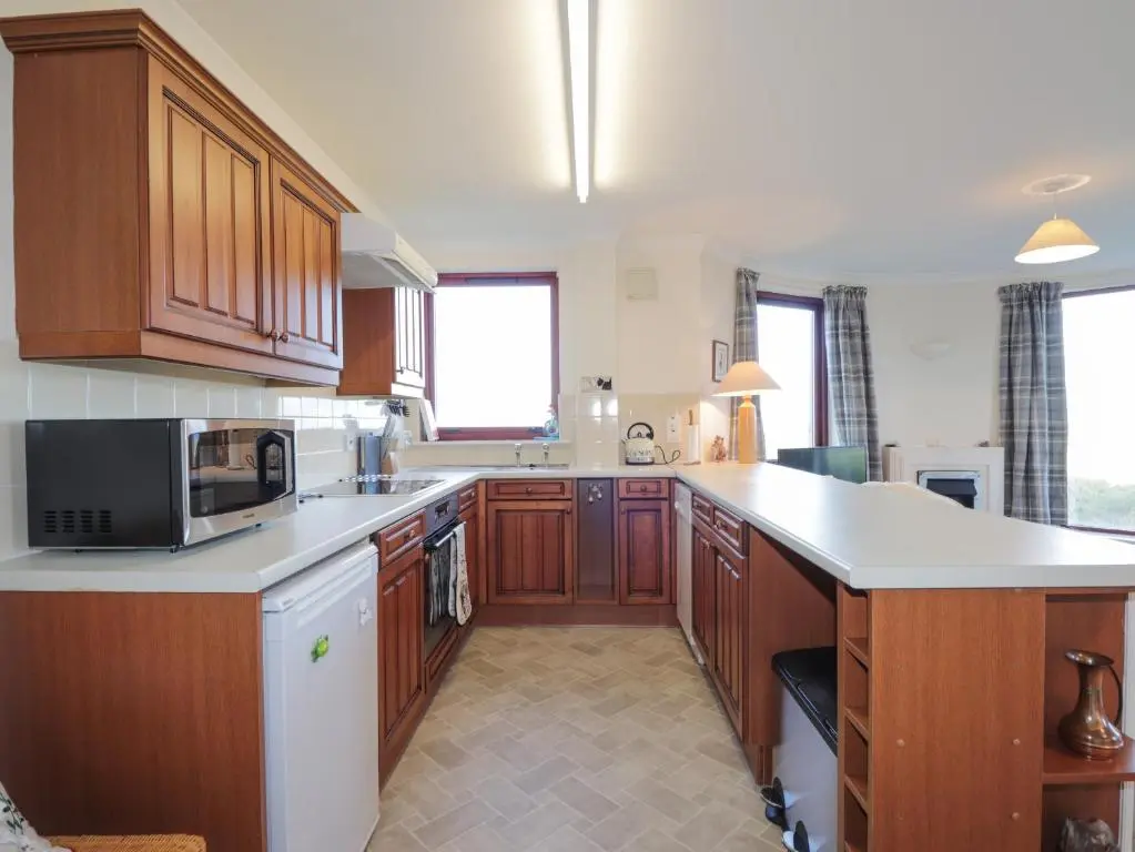 a large kitchen with wooden cabinets and a microwave at Aurora View in Forres