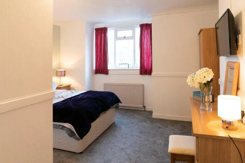 a bedroom with a bed and a window with red curtains at Dunedin House -Contractors - Business Travellers in Huntly