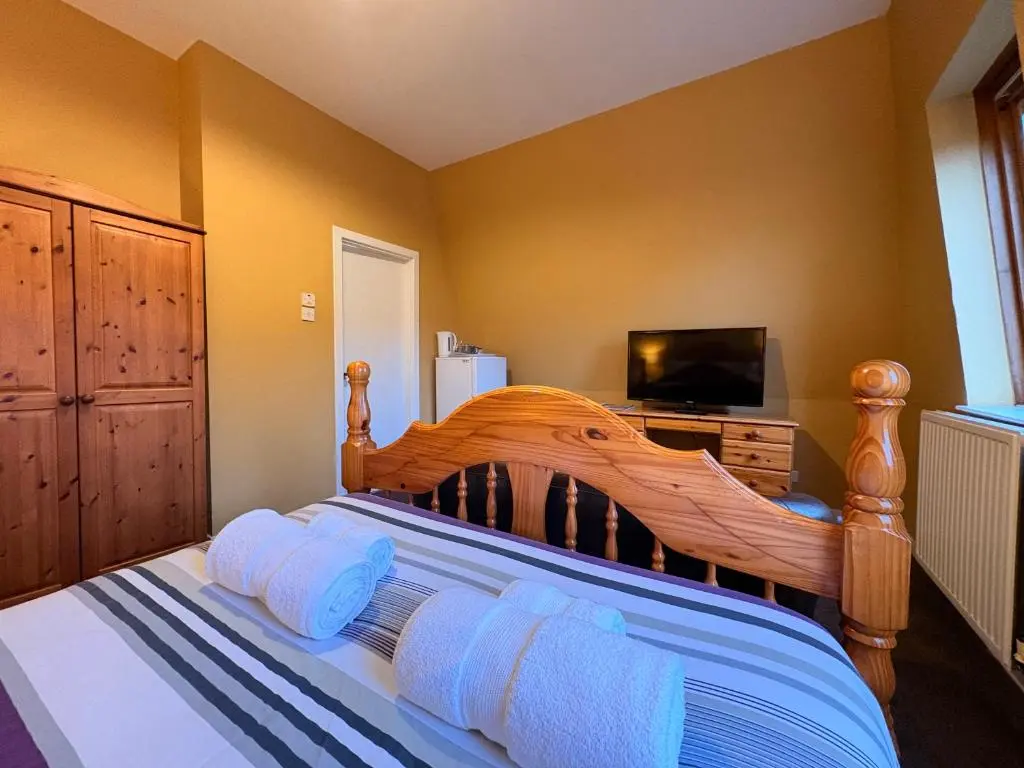 a bedroom with a large wooden bed with a flat screen tv at Winmar in Inverness