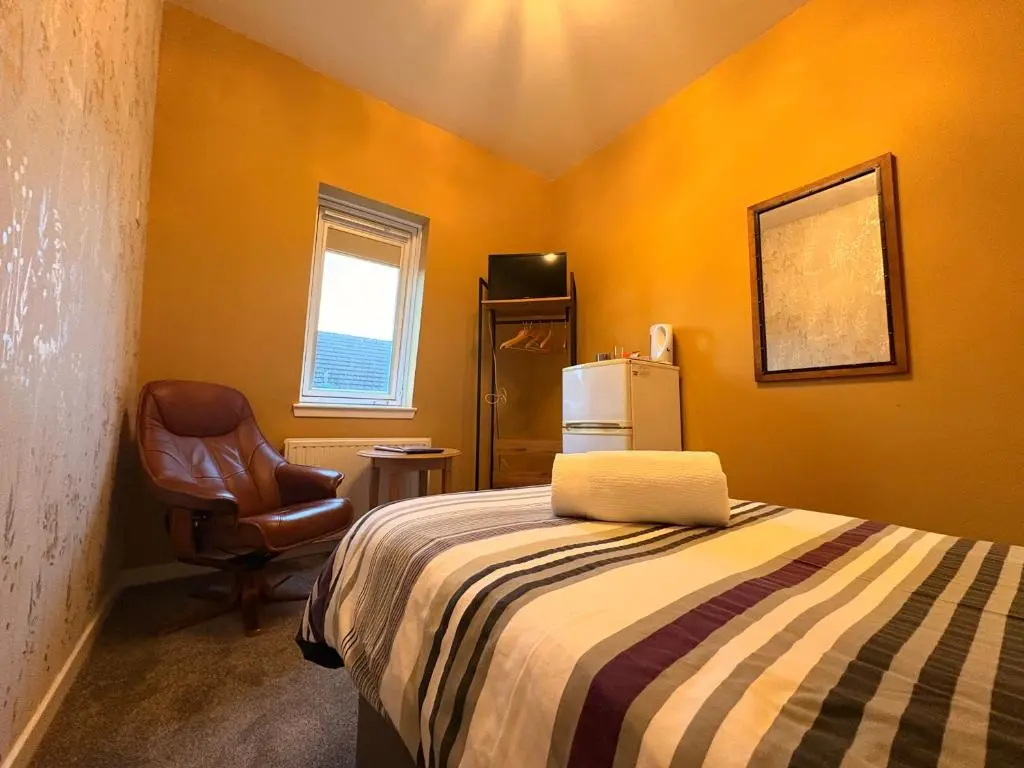 a small room with a bed and a chair at Winmar in Inverness