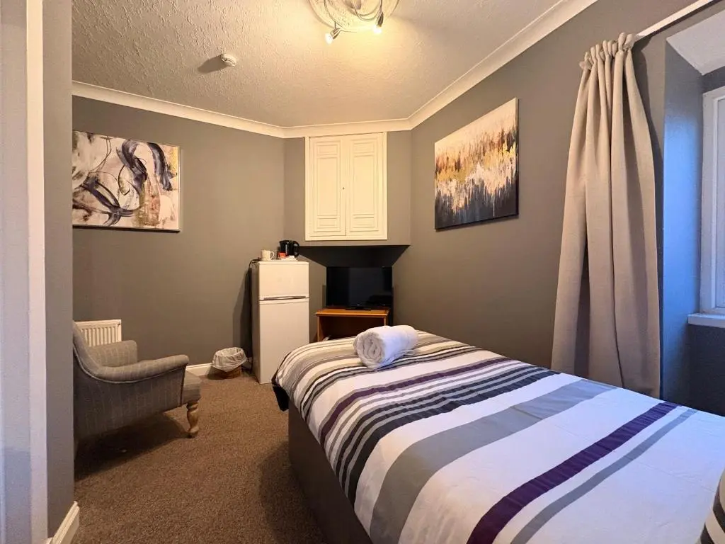 a bedroom with a bed and a chair and a window at Winmar in Inverness