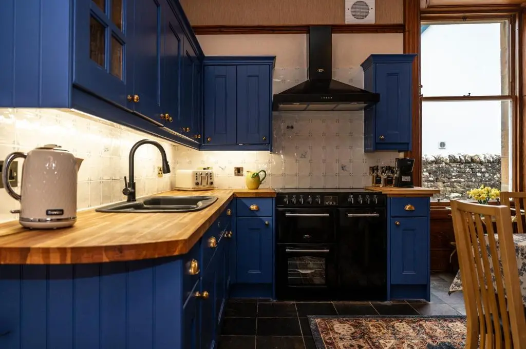 a blue kitchen with a sink and a stove at The Old Bank House Self Catering Apartment Dornoch in Dornoch