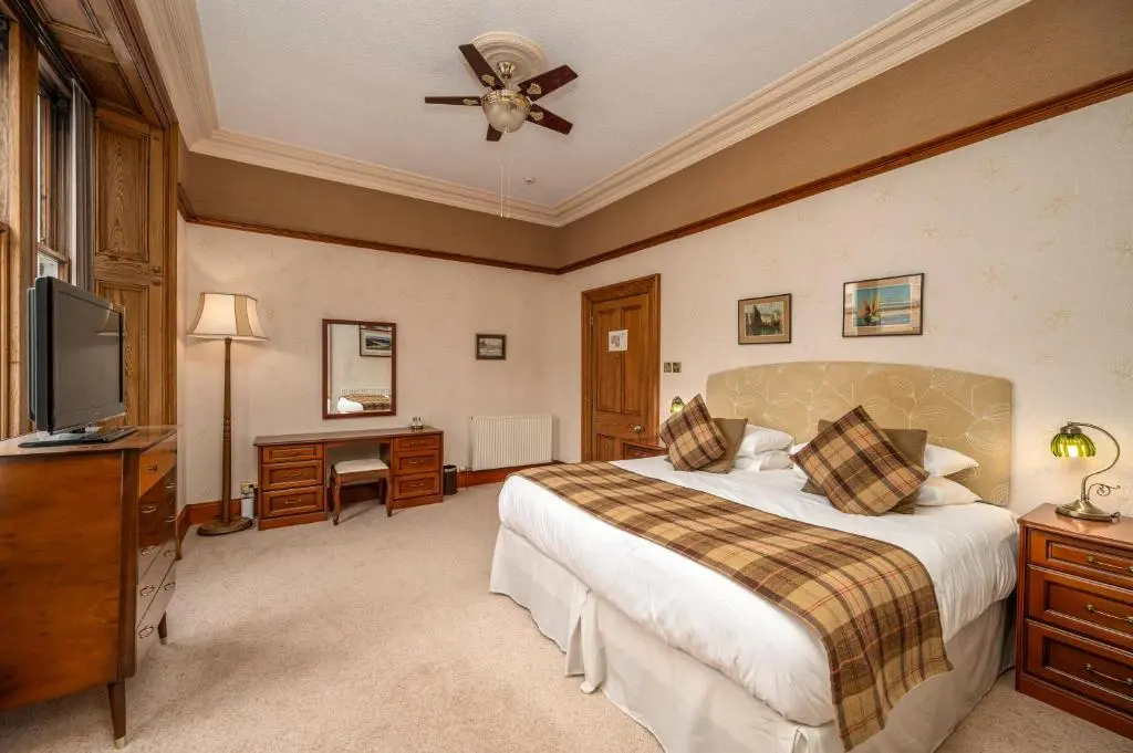 a bedroom with a bed and a television and a desk at The Old Bank House Self Catering Apartment Dornoch in Dornoch