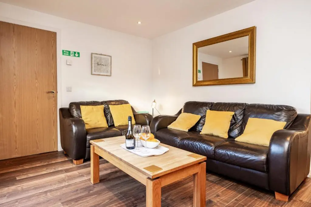 a living room with a leather couch and a table at Bright House with Garden & Patio in Market Town in Inverurie