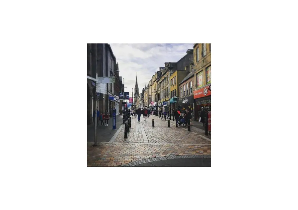 a city street with people walking down the street at Grey Apartment in Inverness
