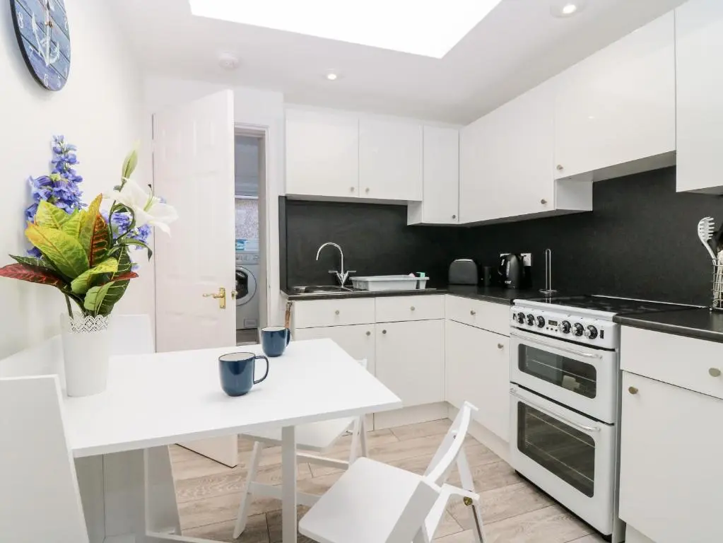 a kitchen with white cabinets and a white table with a white table sidx sidx sidx at Seaspray Cottage in Buckie