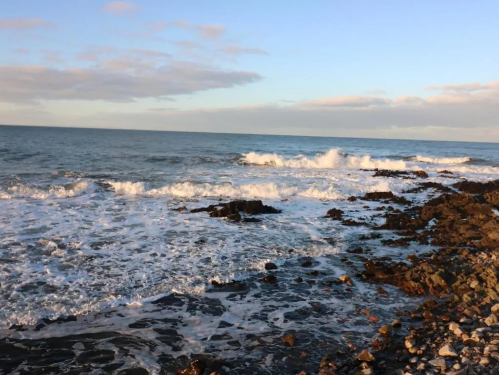 a beach with waves crashing on the rocks at Seaspray Cottage in Buckie