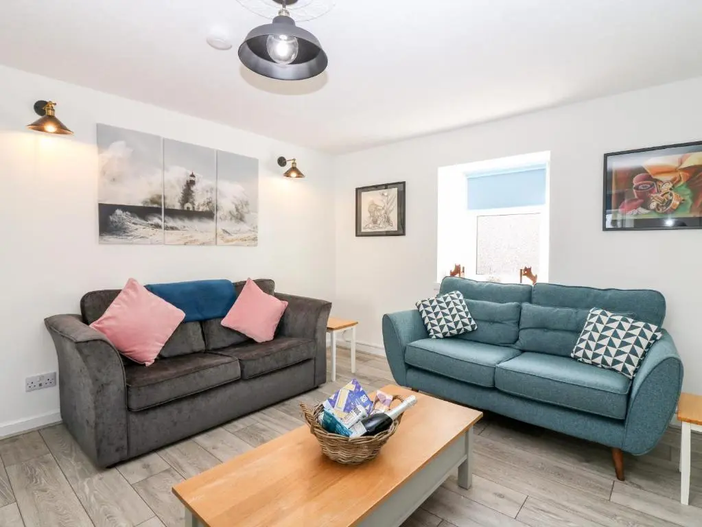 a living room with two couches and a table at Seaspray Cottage in Buckie
