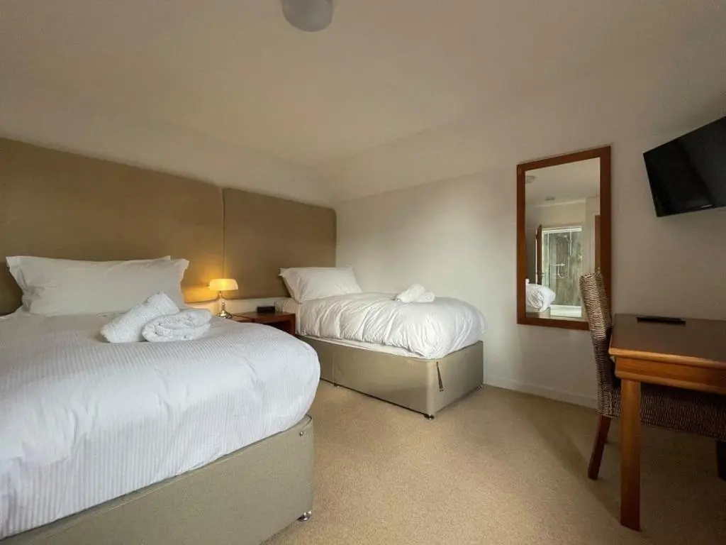 a hotel room with two beds and a mirror at Balloan Steading East in Dornoch
