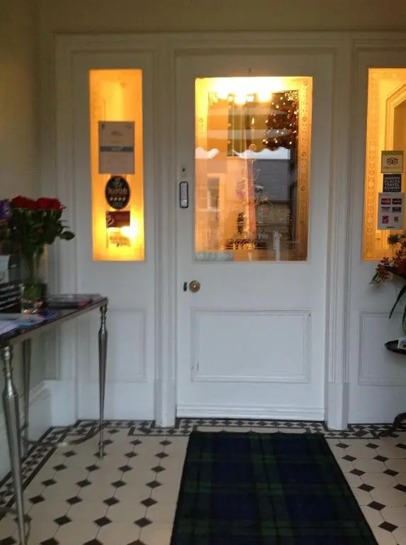 a hallway with a white door and a green rug at Moraydale Guest House in Elgin