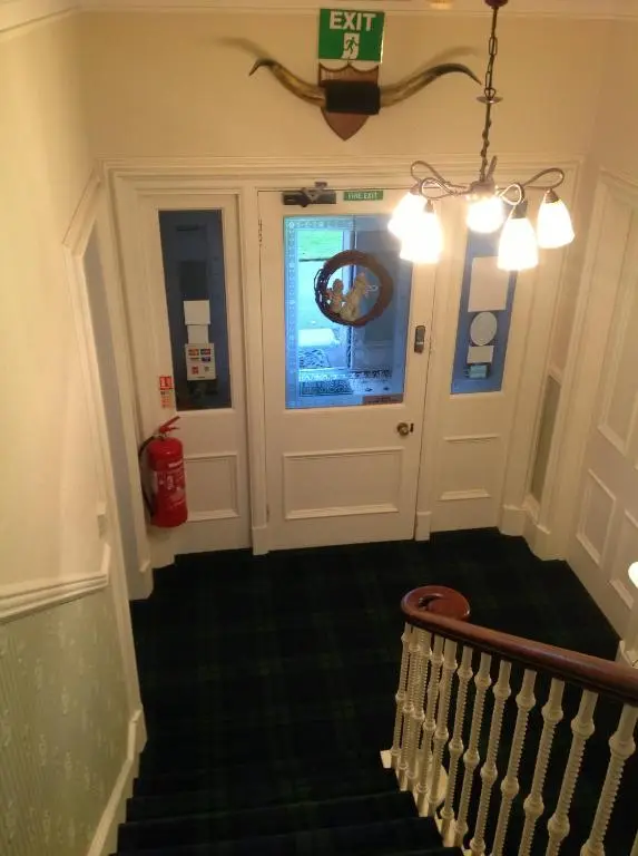 a hallway with a door and stairs with a fire hydrant at Moraydale Guest House in Elgin