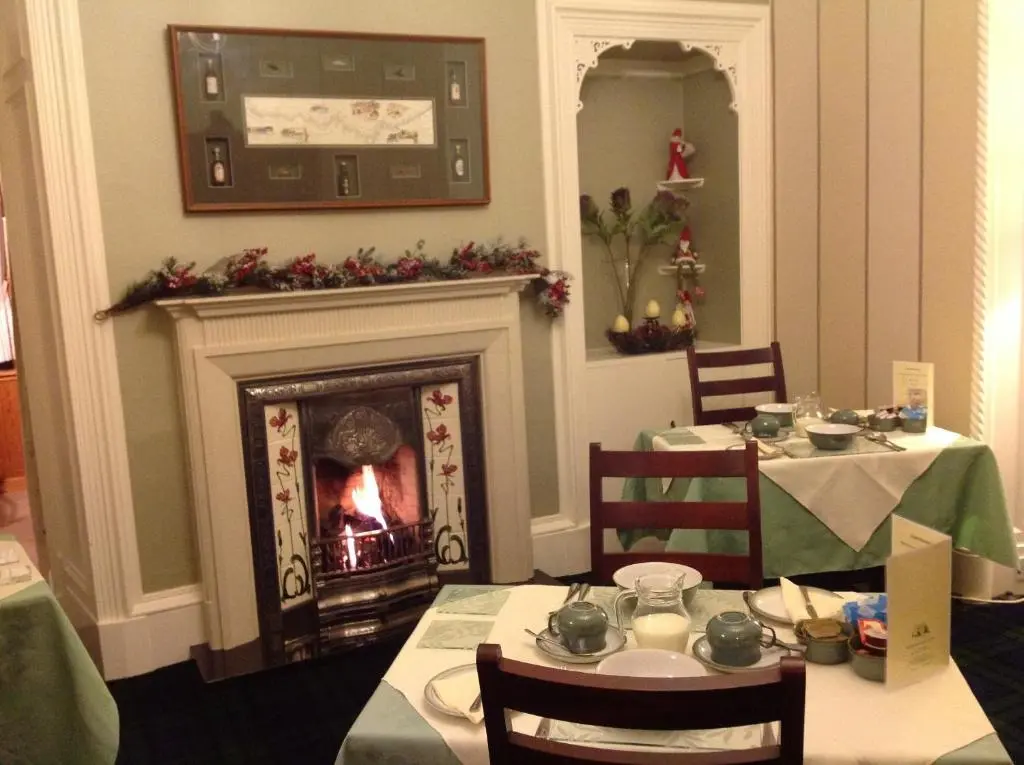 a dining room with two tables and a fireplace at Moraydale Guest House in Elgin