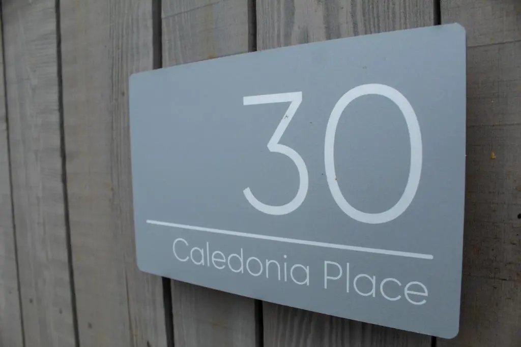 a sign that reads caledonian place on a wooden wall at Alpine View - a cosy Aviemore House in Aviemore
