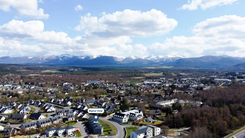 an aerial view of a town with snow covered mountains at Alpine View - a cosy Aviemore House in Aviemore