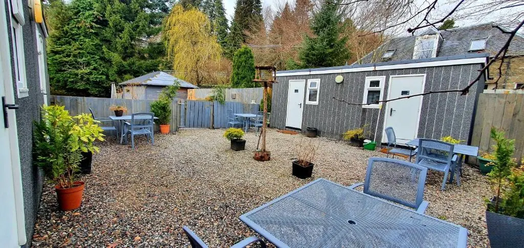 a backyard with chairs and a table and a fence at Kingussie Garden Cabins in Kingussie