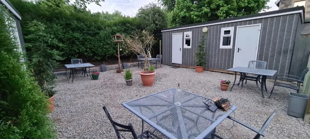 a backyard with tables and chairs and a shed at Kingussie Garden Cabins in Kingussie