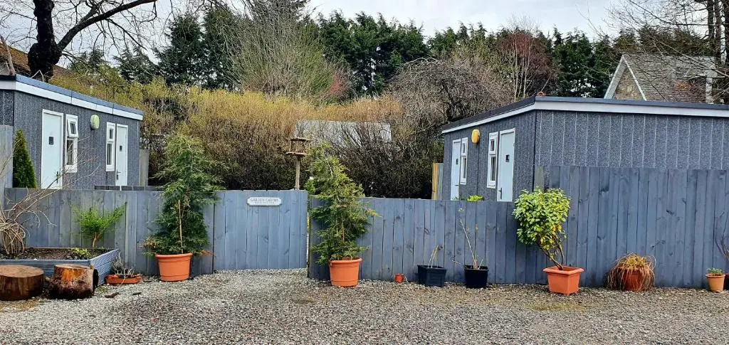 a blue fence with a bunch of potted plants at Kingussie Garden Cabins in Kingussie