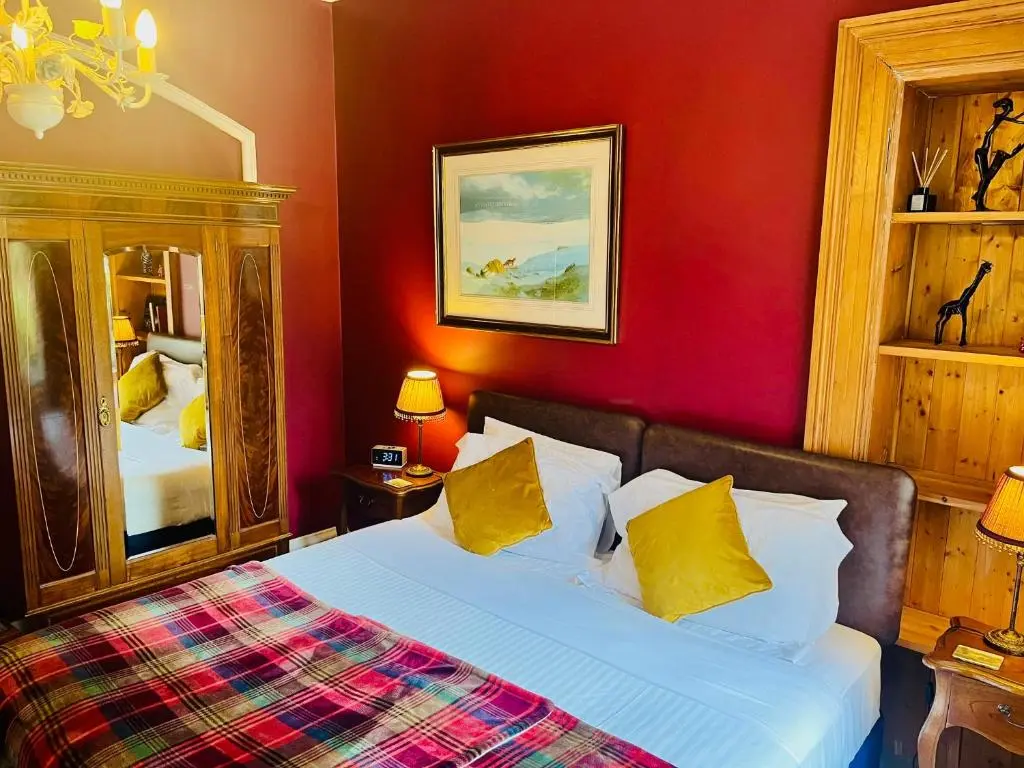 a bedroom with a bed with red walls and yellow pillows at Ladies Lodge Inverness in Inverness