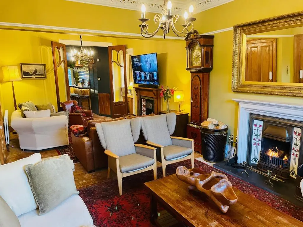 a living room with yellow walls and a fireplace at Ladies Lodge Inverness in Inverness