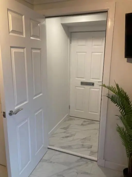 a hallway with a white door and a potted plant at Modern seaside apartment ,Lossiemouth, Moray in Lossiemouth