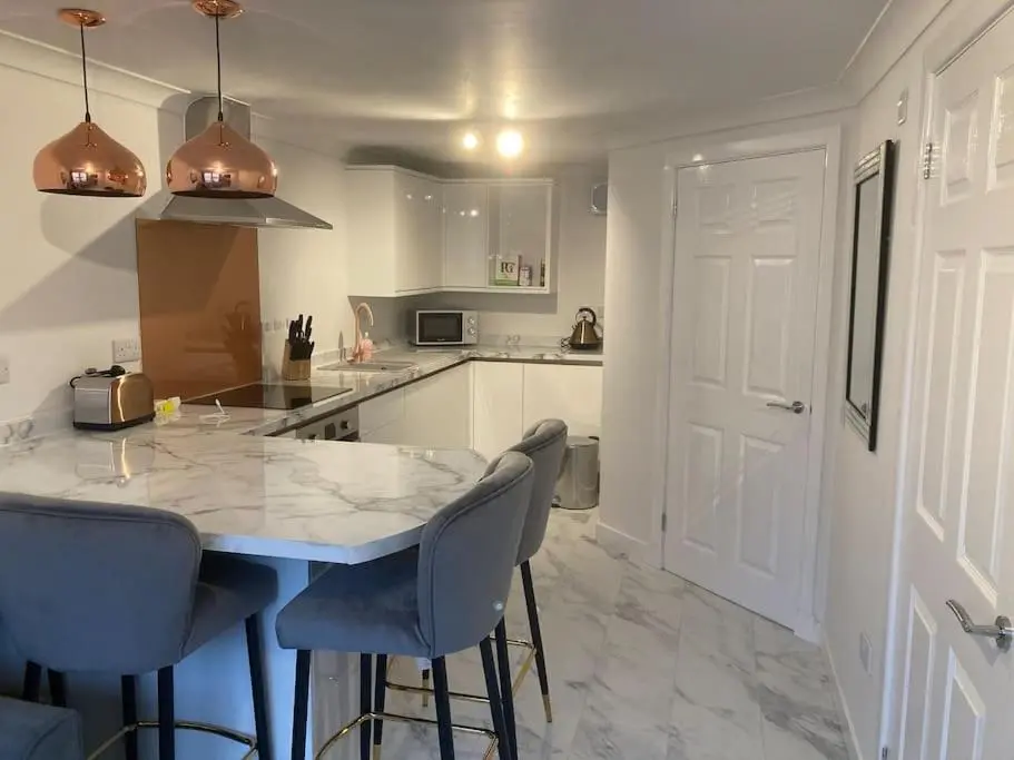 a kitchen with a marble counter top and blue chairs at Modern seaside apartment ,Lossiemouth, Moray in Lossiemouth
