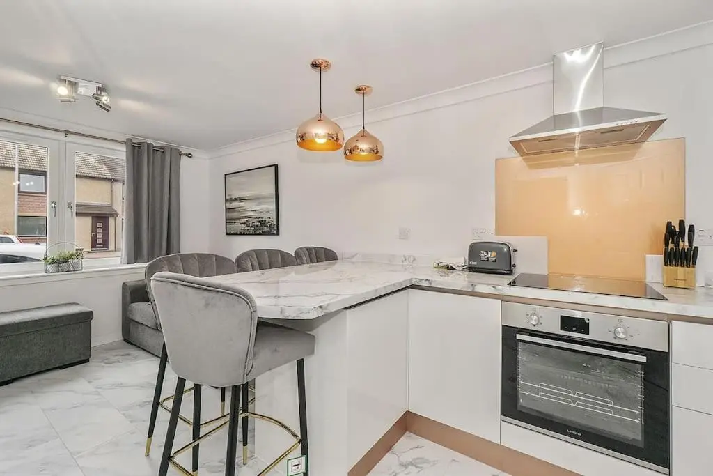 a kitchen with a counter and some chairs in it at Modern seaside apartment ,Lossiemouth, Moray in Lossiemouth
