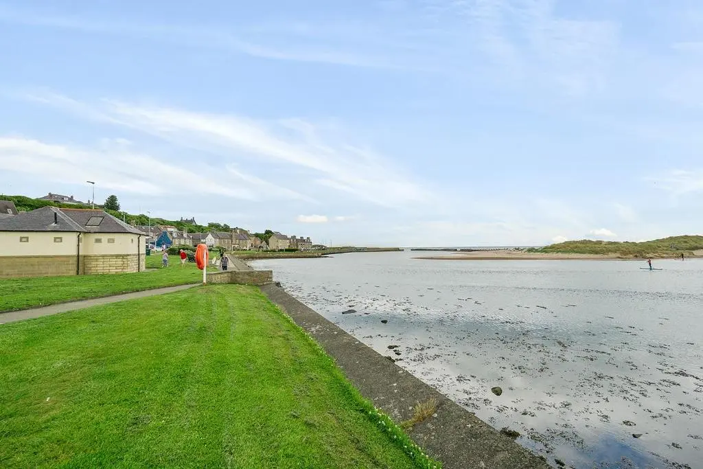 a large body of water with a house and grass at Modern seaside apartment ,Lossiemouth, Moray in Lossiemouth