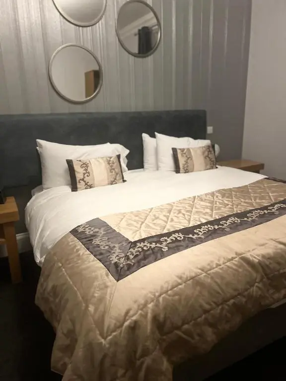 a bedroom with a large bed with two mirrors at The Aberlour Hotel in Aberlour