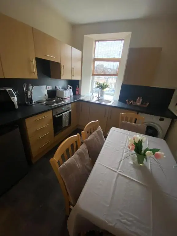 a kitchen with a table with a vase of flowers on it at Inverness city apartments - Innes in Inverness