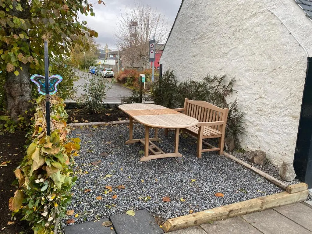 a wooden table and bench sitting next to a building at Butterfly Cottage in Grantown on Spey