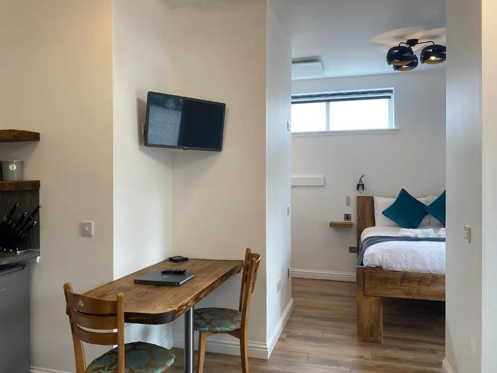 a room with a table and a bedroom with a bed at Butterfly Cottage in Grantown on Spey