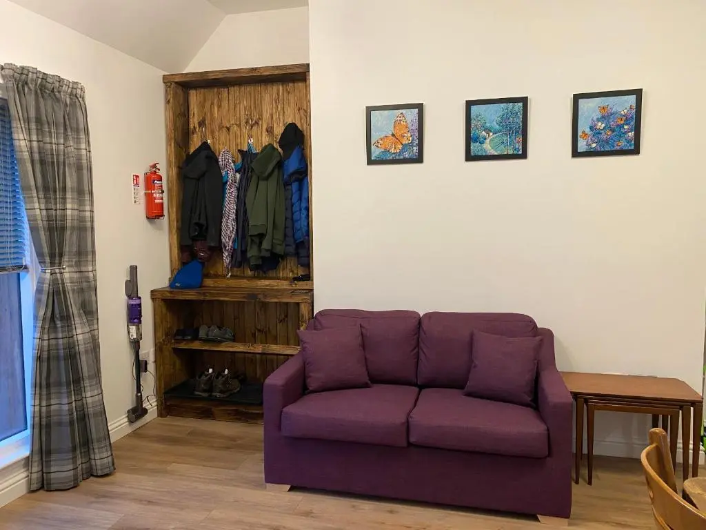 a purple couch in a living room with a closet at Butterfly Cottage in Grantown on Spey