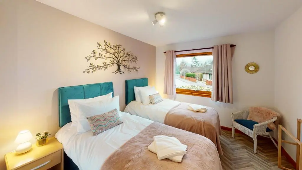 a bedroom with two beds and a window at Burnside Pines in Aviemore