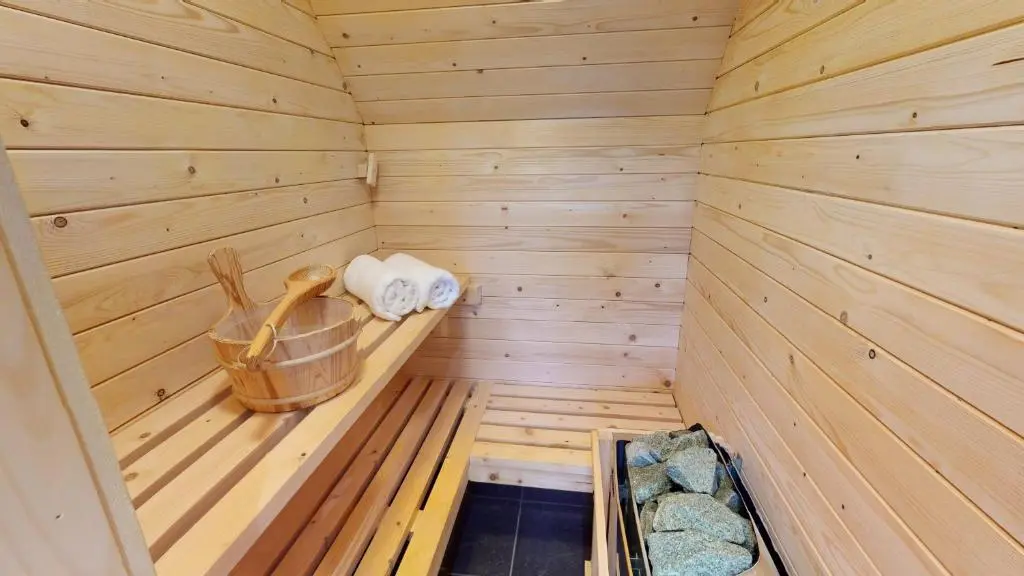 a wooden sauna with a bench and towels in it at Burnside Pines in Aviemore
