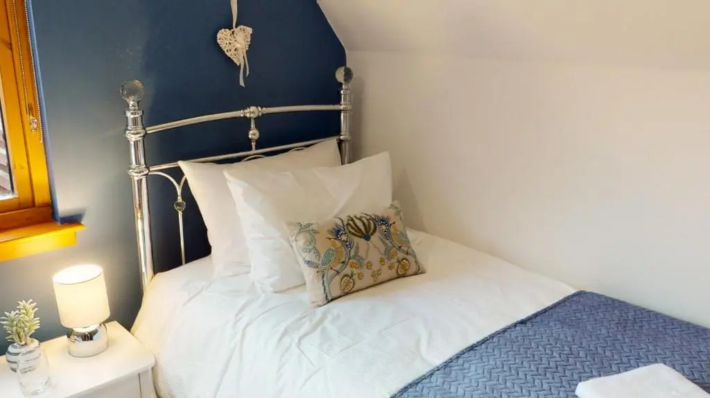 a bed with white sheets and a pillow on it at Burnside Pines in Aviemore