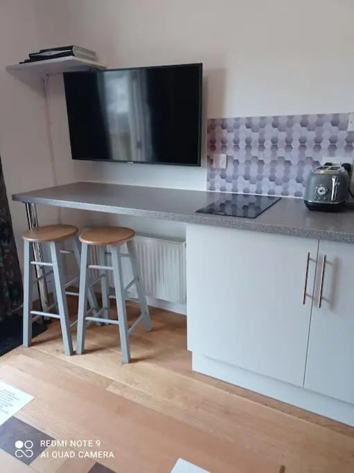 a kitchen with a counter with stools and a counter top at Avalon Studio. Comfy well equipped cosy studio. in Aviemore