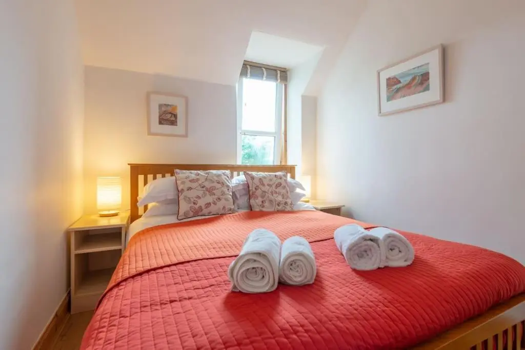 a bedroom with a red bed with towels on it at The 'Fairy Hill' Apartment in Inverness