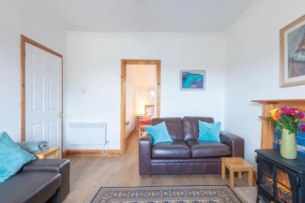 a living room with a leather couch and blue pillows at The 'Fairy Hill' Apartment in Inverness
