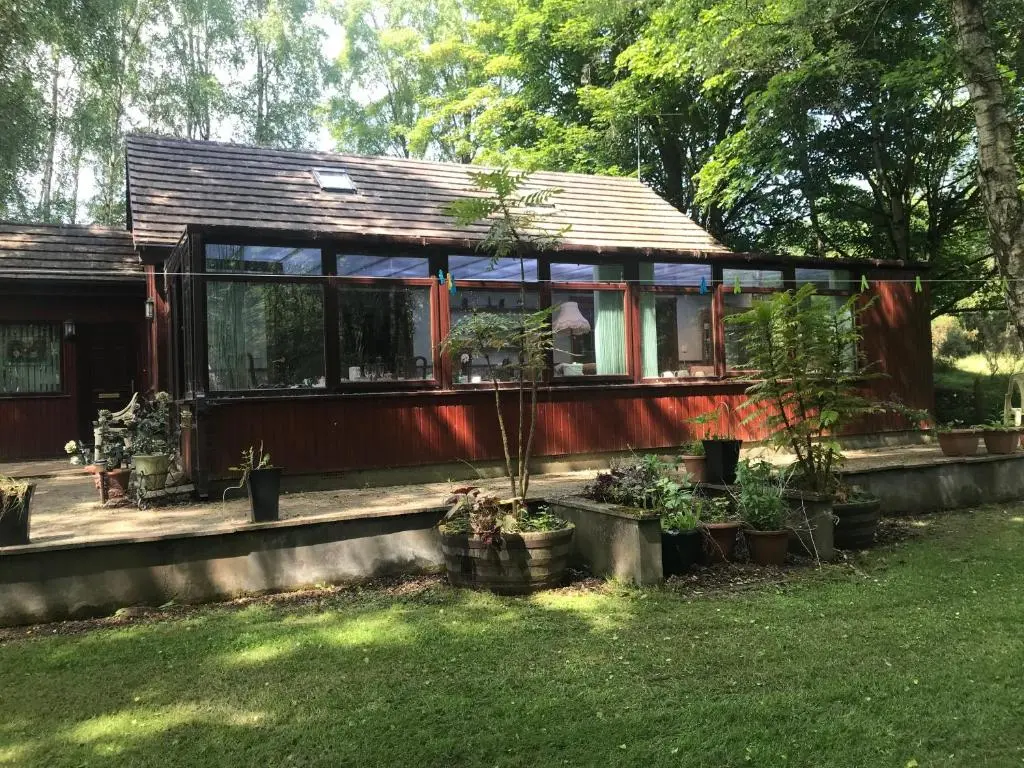 a house with a lot of windows and potted plants at Pine Chalet in Muir of Ord