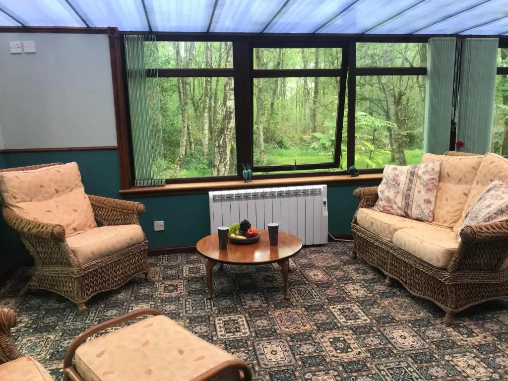 a living room with two chairs and a table at Pine Chalet in Muir of Ord