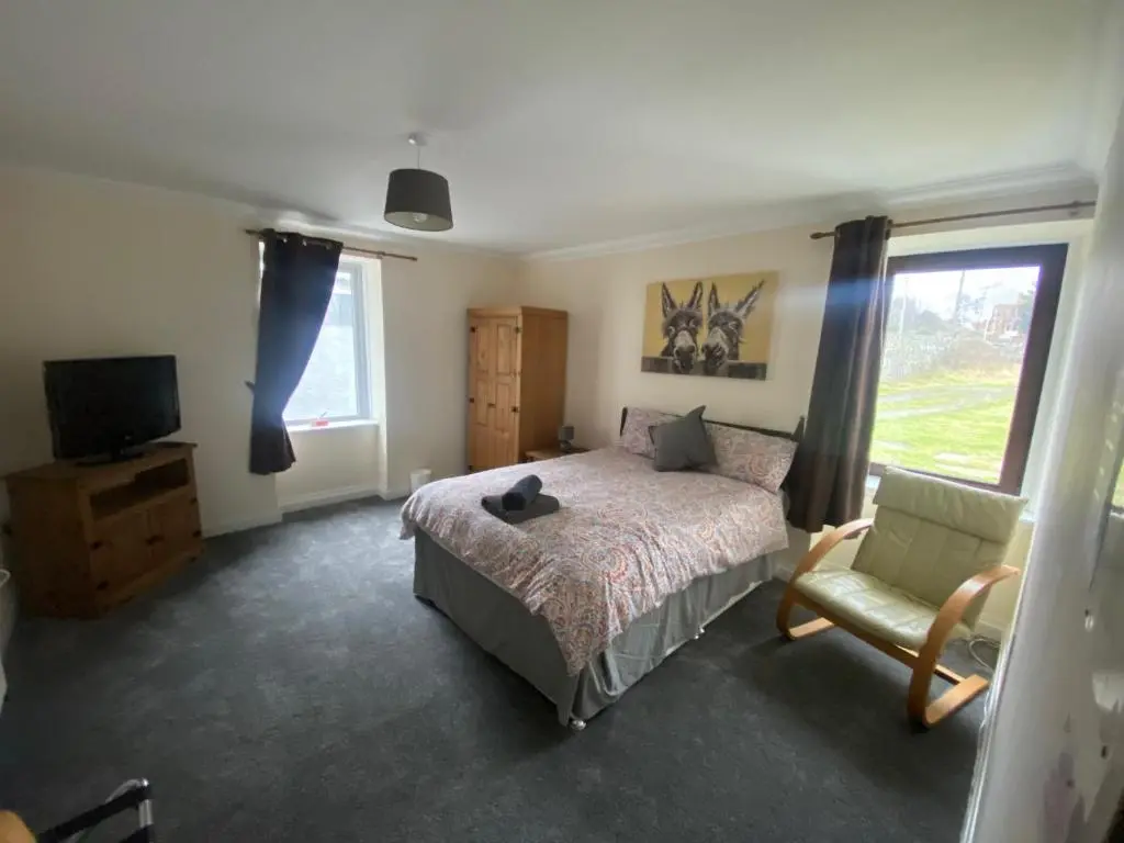 a bedroom with a bed and a chair and a television at Little Ship Inn Rooms in Invergordon