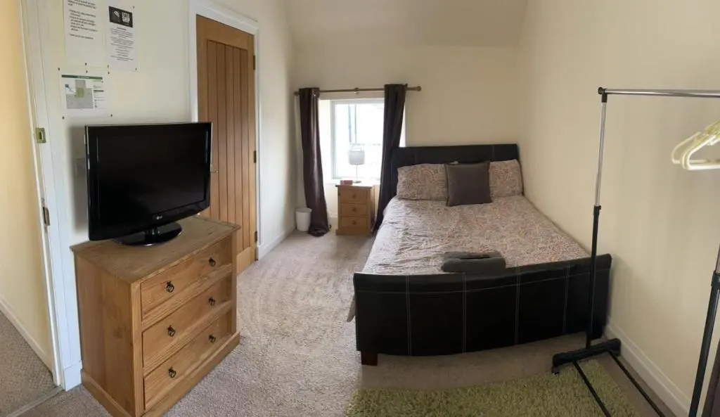 a bedroom with a bed and a flat screen tv at Little Ship Inn Rooms in Invergordon
