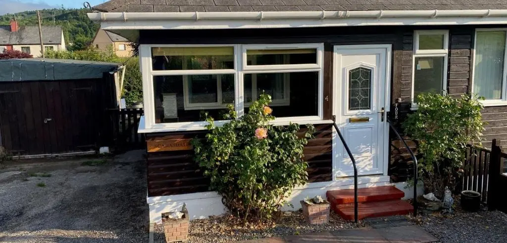 a small house with a white door and windows at No 4 the Highlands in Strathpeffer