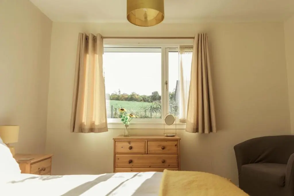 a bedroom with a bed and a window with a dresser at No 4 the Highlands in Strathpeffer
