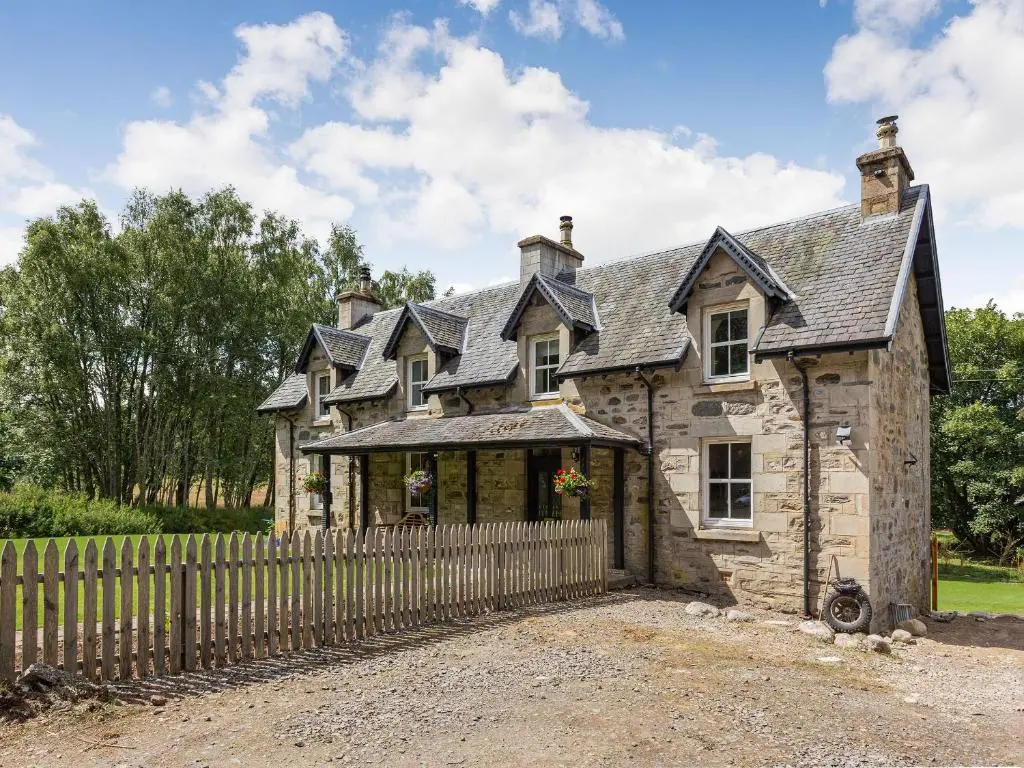 an old stone house with a wooden fence at New Cottage in Farr