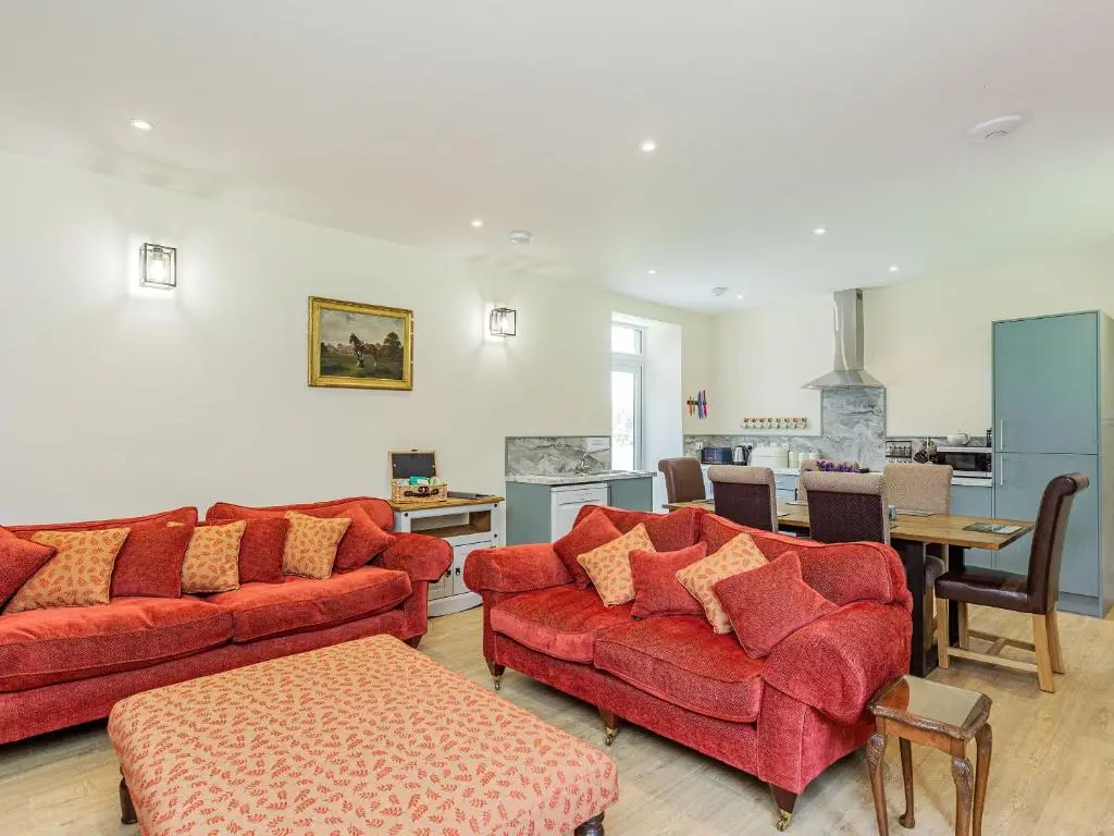 a living room with red couches and a kitchen at New Cottage in Farr